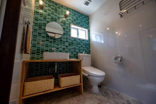 a bathroom with a toilet and a green tiled wall at 日向サーフキャンプ111 in Hyuga