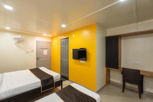 a bedroom with a bed and a tv and a desk at Hotel Ellora Park in Pune