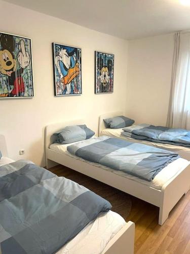três camas num quarto com pinturas na parede em Messe - Augsburg - Zentrum - 2 Zimmer - 3 Personen em Augsburg