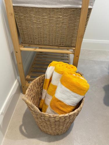 a basket of towels sitting next to a chair at Sunny Palm Cottage Byron Bay - Brand New in Byron Bay