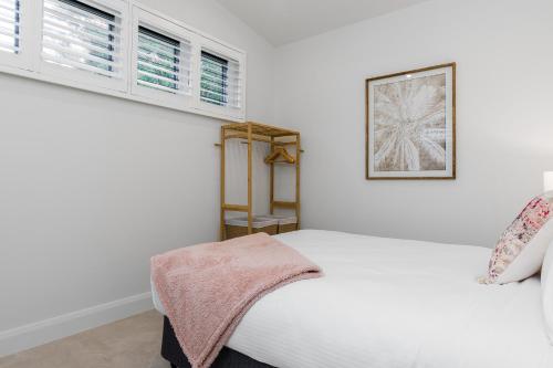 a white bedroom with a bed and two windows at Sunny Palm Cottage Byron Bay - Brand New in Byron Bay