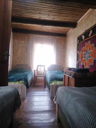 a room with three beds and a window with a chair at "Dzveli galavani" Tusheti Diklo "ძველი გალავანი" in Diklo