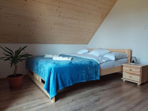 a bedroom with a large bed with a blue blanket at Domek Rodakówka in Krempna