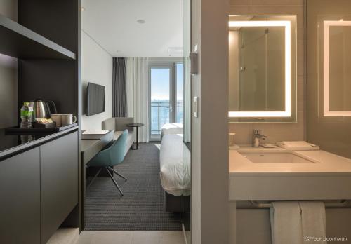 a bathroom with a sink and a desk and a mirror at Grab The Ocean Songdo in Busan