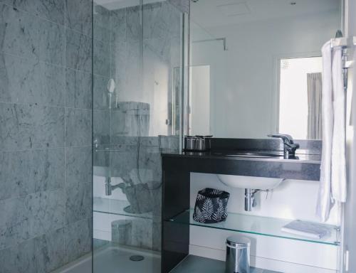 a bathroom with a glass shower and a sink at Le Manoir Hôtel in La Rochelle