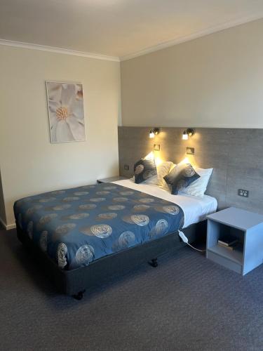 a bedroom with a large bed with a blue comforter at Colac Central Motel in Colac