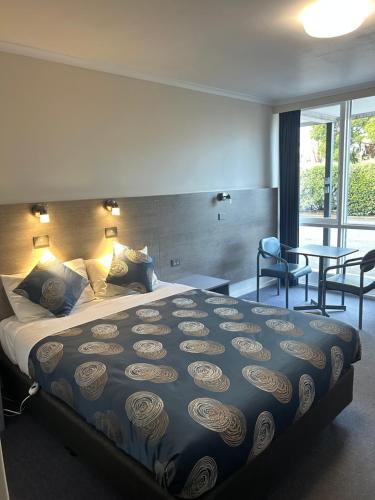 a hotel room with a large bed and a table at Colac Central Motel in Colac