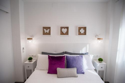 1 dormitorio con cama blanca y almohadas moradas en Apartamentos Linersol, en Málaga