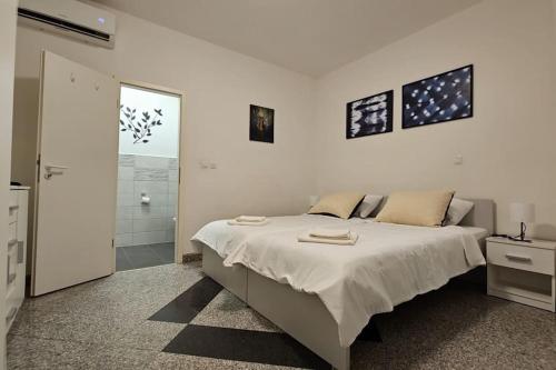 een witte slaapkamer met een groot bed en een badkamer bij Cozy Hideaway in Ljubljana