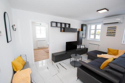 a living room with a black couch and yellow pillows at Apartmani Kac in Karlovac