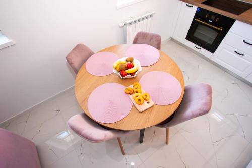 a round wooden table with pink chairs with food on it at Apartmani Kac in Karlovac