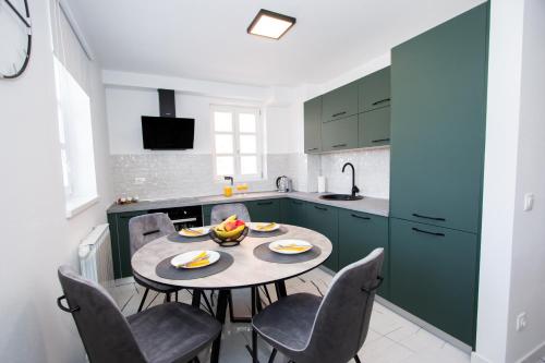 a kitchen with green cabinets and a table and chairs at Apartmani Kac in Karlovac