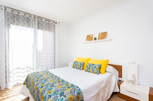 een witte slaapkamer met een bed met gele kussens bij 123 Sotavento Beach and Sun By Sunkeyrents in La Tejita