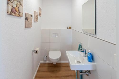 ein weißes Bad mit einem WC und einem Waschbecken in der Unterkunft Knus in Dornum