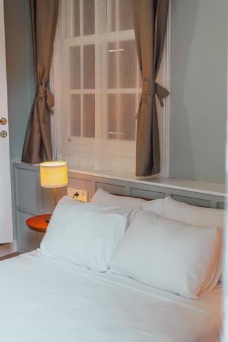 a bed with white pillows in a bedroom with a window at Ivy Ayvalık Butik Otel in Ayvalık