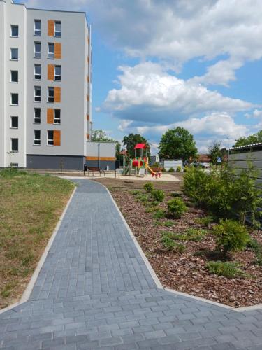 a brick walkway in front of a building with a playground at Apartament MajaHouse in Nowa Sól