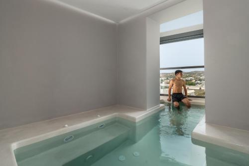 Un uomo in piedi in una piscina in una casa di Uncle's House luxury Suites ad Adámas
