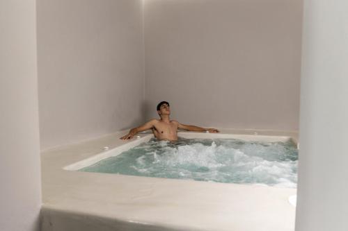 a man is sitting in a bath tub at Uncle's House luxury Suites in Adamas