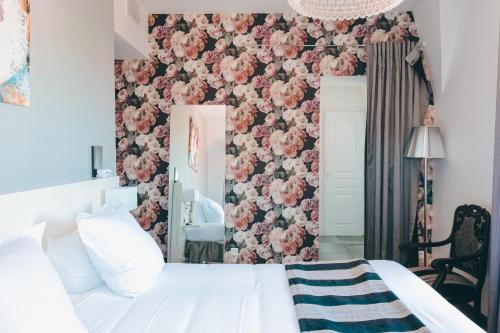 a bedroom with a white bed and a pink floral wall at Le Manoir H&ocirc;tel in La Rochelle