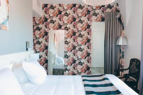 a bedroom with a white bed and a pink floral wall at Le Manoir Hôtel in La Rochelle