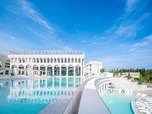 a large building with a swimming pool in front of it at The Siena Resort in Seogwipo
