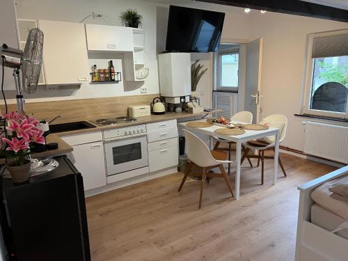 a kitchen with white cabinets and a table and chairs at Ferienwohnung LandLeben für 2-3 Personen in Edesheim