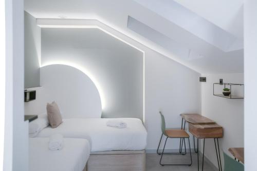 a white room with a bed and a table at Coliving Compostela in Santiago de Compostela