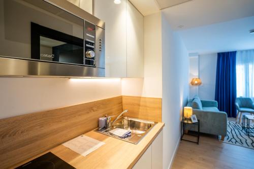 a kitchen with a sink and a living room at abba Apartments Playa de Gros San Sebastián in San Sebastián
