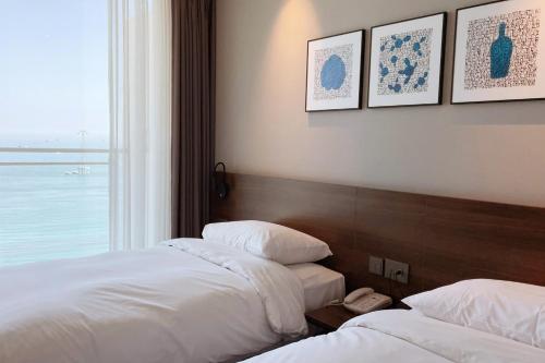 two beds in a hotel room with a window at Grab The Ocean Songdo in Busan