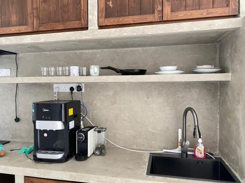 um balcão de cozinha com comodidades para preparar café e um lavatório em Rumatepi em Malaca