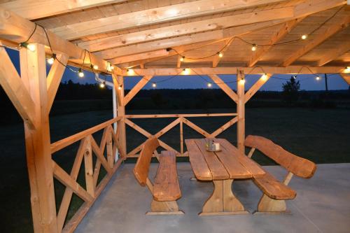 a wooden picnic table under a pavilion with lights at Domek mamy in Tykocin