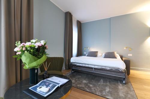 a hotel room with a bed and a table with flowers at PRESTIGE BOUTIQUE APARTHOTEL - Piazza Duomo View in Milan