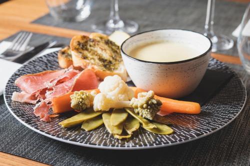 a plate with meat and vegetables and a cup of milk at Logis Le Saint Hubert in Haybes