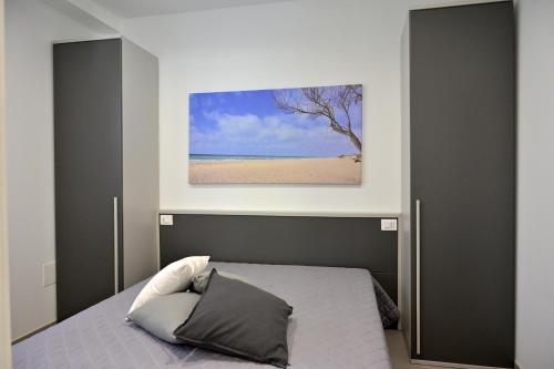 una camera con letto e una foto di una spiaggia di Altamarea Beach Experience Villetta SA a Marina di Pescoluse