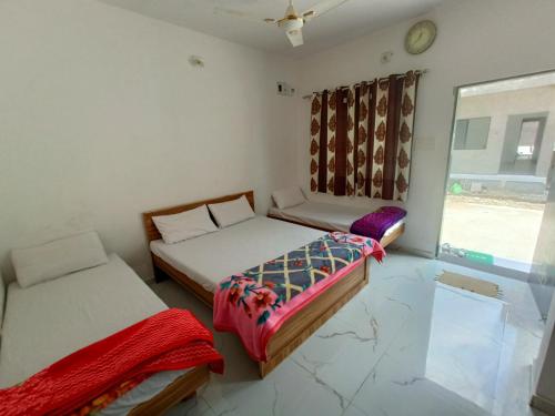 two beds in a room with a window at SHIV SHAKTi HOMESTAY in Kevadia