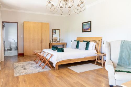 ein Schlafzimmer mit einem großen Bett und einem Stuhl in der Unterkunft Lovane Boutique Wine Estate and Guesthouse in Stellenbosch