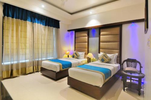 een slaapkamer met 2 bedden, een stoel en een raam bij Hotel The Pearl in New Delhi