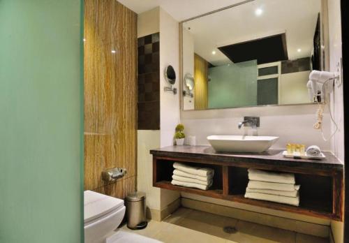 ein Badezimmer mit einem Waschbecken, einem WC und einem Spiegel in der Unterkunft Hotel The Pearl in Neu-Delhi