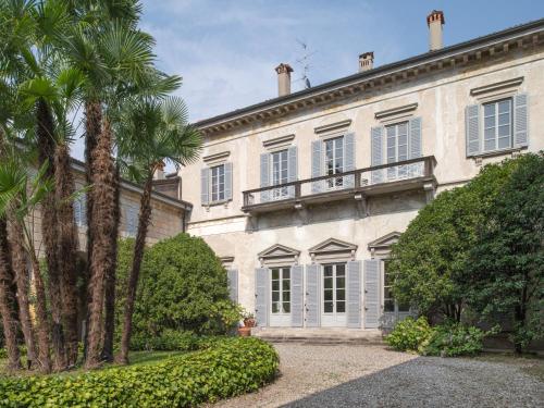 une grande maison blanche avec des palmiers devant elle dans l'établissement Villa Galimberti Maison De Charme, à Osnago