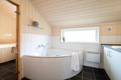 eine weiße Badewanne im Bad mit Fenster in der Unterkunft Resort 1 Beach House B 144 in Großenbrode