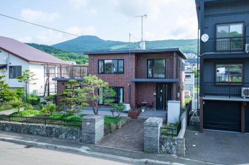 a red brick house with mountains in the background at The Villa Moiwa in Sapporo