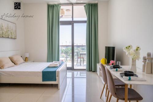 a bedroom with a bed and a table with chairs at Mira Holiday Homes - Spacious Studio with Balcony - Free Wifi in Dubai