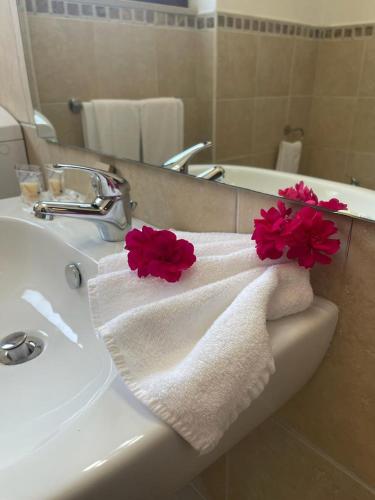 a bathroom sink with a towel with red flowers on it at San Raffaele Guest House in Villasimius