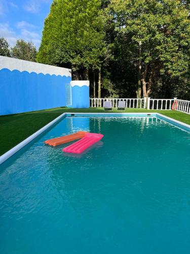 a large swimming pool with two red chairs in the water at QUINTA DONA MANUELA in Formariz
