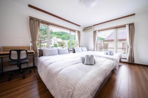 a bedroom with two beds and a desk and windows at The Villa Moiwa in Sapporo