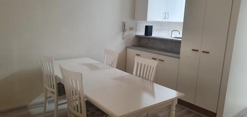een witte keuken met een witte tafel en stoelen bij Beautiful inner city fully renovated ground floor apartment with attached lock-up garage in Canberra