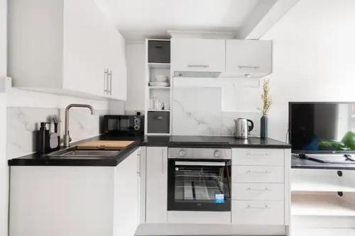 Nice 2 bedroom house in Stowmarket في ستوماركت: مطبخ أبيض مع حوض وموقد