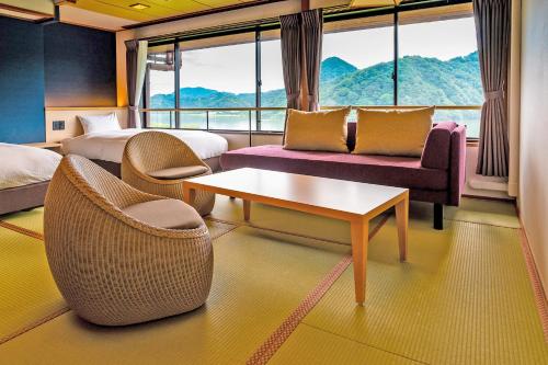a hotel room with two beds and a table and chairs at Ooedo Onsen Monogatari Premium Kinosaki in Toyooka