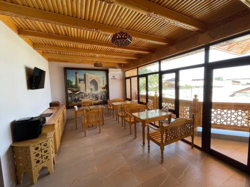 a dining room with tables and chairs and windows at Hanifa Boutique Hotel in Samarkand