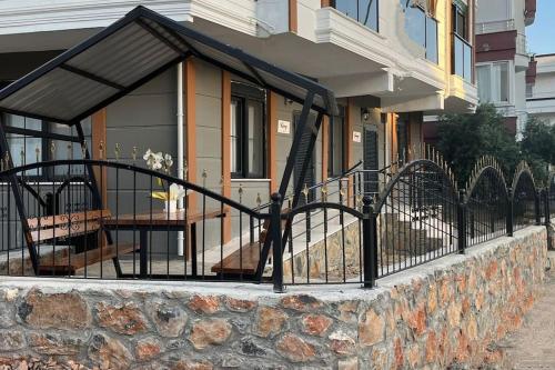 un edificio con una valla y una mesa en un porche en Kumsal Evleri & Güney - Bahçeli, Denize 200m, en Bozyazı